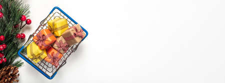 Shopping basket full of christmas gifts wrapped in festive paper with firtree branch isolated on white background. Advertising banner with copy space or place for text.の写真素材