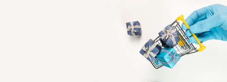Shopping cart or trolley full of gift boxes in hand in glove. Trolley with presents for christmas...