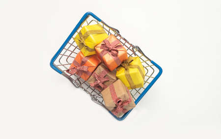 Shopping basket full of yellow wrapped gift boxes. Presents for christmas on white background, top...