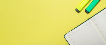 Yellow office desk or table background. Backdrop with notebook or planner with bright markers. Copy...