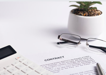 Office desk or table with contract paper, documents, calculator, potted plant, pen and eyeglasses....