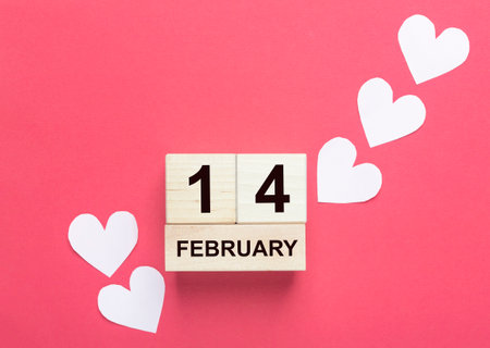 14 february on wooden calendar with pale pink hearts over red background.の写真素材