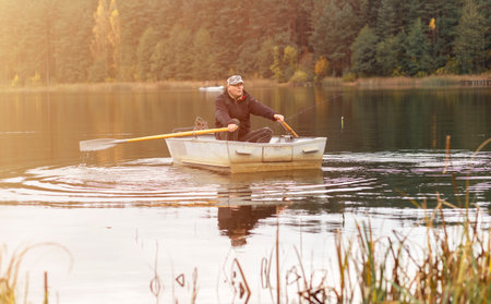 Man sailing or floating in boat and rowing oars on lake.の写真素材