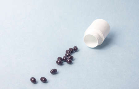 Capsules scattered from jar of pills, homeopathy.の写真素材