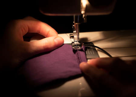 Female hands of tailor or housewife making medical masks from cotton with sewing machine, close up.の写真素材