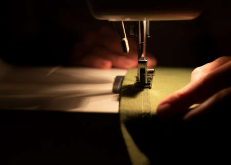 Close up of women hands at textile under needle of sewing machine. Slow fashion concept.の写真素材