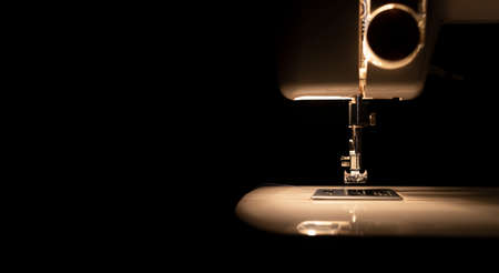 Light from bulb of modern sewing machine in darkness, front view. banner with copy space