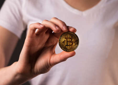 Golden coin of BTC or bitcoin held bu female hand.の写真素材