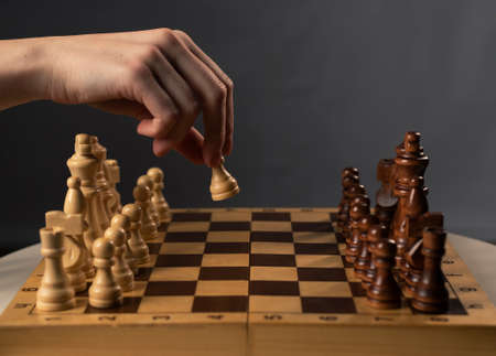 Hand moving white pawn and making first step.