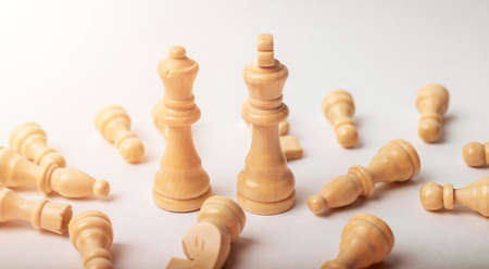Chess white king and queen among fallen figures on white.の写真素材