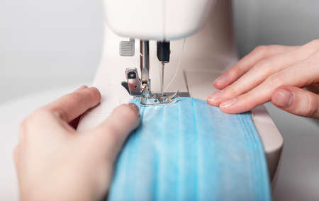 Close up of hands sewing face medical mask on machine, female handsの写真素材