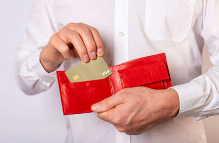 Male hands with red wallet and golden bank plastic card close up.