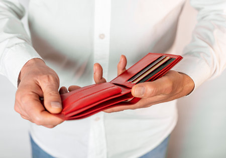 Male hands holding red wallet with bank plastic cards.