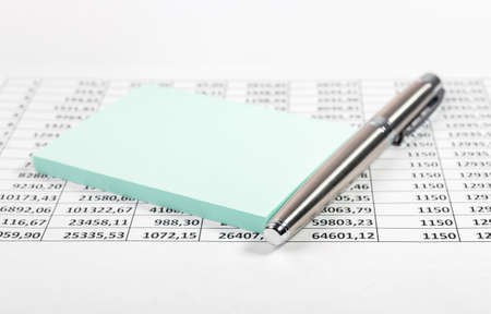 Close up of workplace with pen and sticky note and financial report.