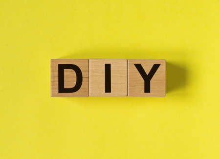 DIY acronym, inscription on wooden cubes on yellow background. Do it yourself conceptの写真素材