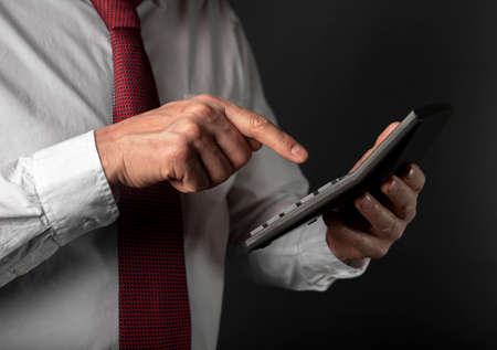 Male hand of businessman holding calculator over black backgroundの写真素材