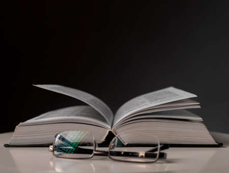 Eyeglasses and open book on black background. Education concept.