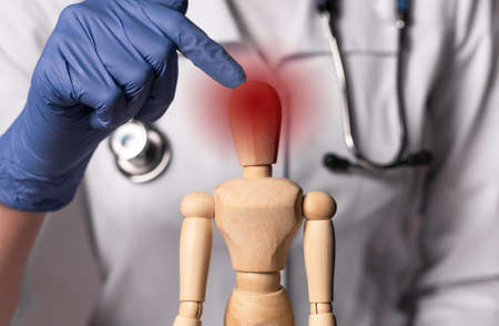 Doctor hand showing headache or pain in head, migraine on wooden dummy.の写真素材