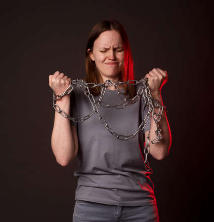 Young woman ties with chain, suffer from despair, psychological problems. Unhappy person with heavy burden concept.の写真素材