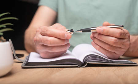 Close up man taking notes on meeting, ready to write down schedule, events, appointments in planner...