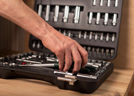 Male hand with socket ratchet handle and metal steel hex socket, hexagon metal head. Industrial metal tool, close up.の写真素材