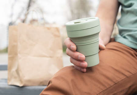 Collapsible silicon eco cup for takeaway coffee. Male hand with sustainable mug.の写真素材