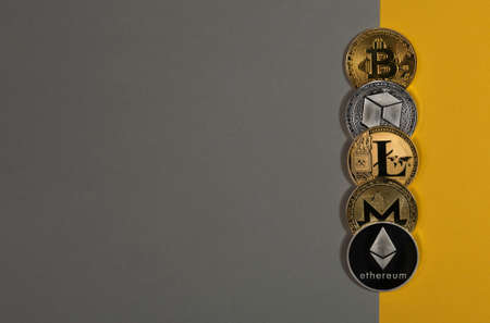 Different shining cryptocurrency coins, crypto currency. Bitcoin, litecoin, ethereum, monero and NEO on yellow and gray background. Banner with copy space.の写真素材