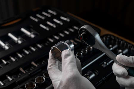 Male hands in gloves with steel socket ratchet handle and metal steel hex socket. Car and home...