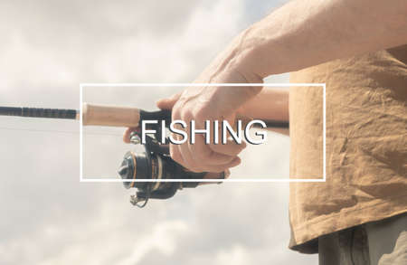 Fishing inscription sign on photo of male hands with reel rod in hands on sunny summer day.