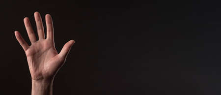 Male hand palm gesturing hello or hi over black background. greeting gesture. Banner with copy space.の写真素材
