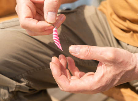 Pink silicon bait slug in male hands close up. Trout fishing with lure concept.