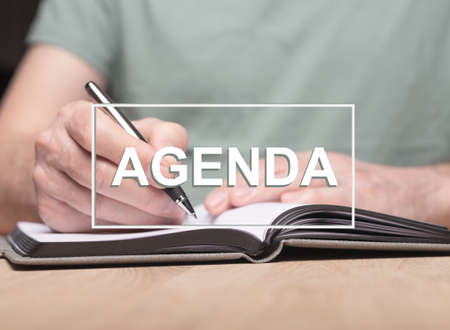 Agenda word with photo of male hands writing in planner or organizer.の写真素材