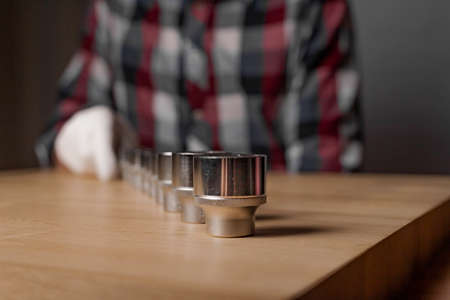 Row of metal steel hex sockets or metal heads on wood table. Repair metal tool line.