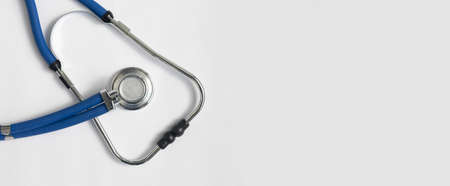 Metal blue sthethoscope on white background with copy space. Medical banner with hospital tool.