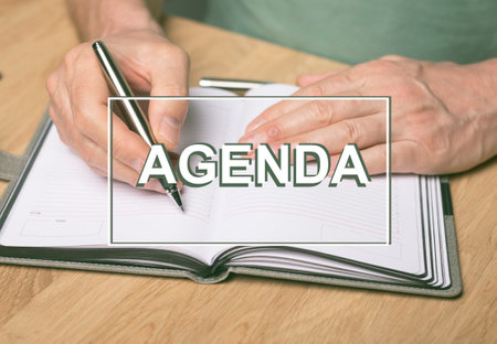 Agenda word. Inscription on photo of hands writing in planner or organizer.の写真素材