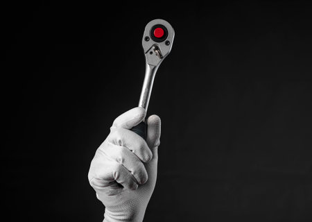 Socket ratchet handle in hand in glove on black background with copy space.の写真素材