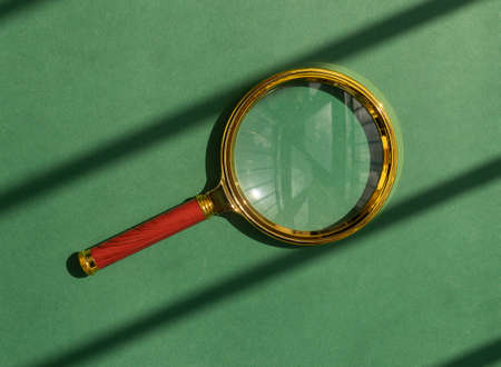 Magnifying glass over green background with sun light. Magnifier as concept of finding answers.の写真素材