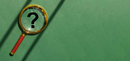 Magnifying lens over green background with copy space. Eco banner with golden magnifier, question mark inside and place for text.の写真素材