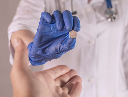 Patient hand receiving and taking pill from doctor hand. Pharmacist giving medicine to male palm, pov.の写真素材