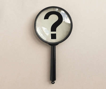 Magnifying glass over pale beige background with question mark. Magnifier with interrogation sign.の写真素材