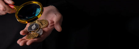 Ethereum and heap of other crypto currency coins in male hand over black background with copy space.