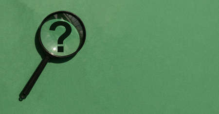Magnifying lens over green background with copyspace. Banner with magnifier, question mark and place for text.の写真素材