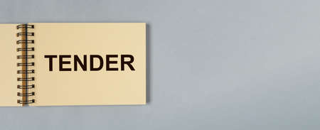 Tender word on notebook paper on blue gray background with copy space for text. Business banner with copyspace.の写真素材