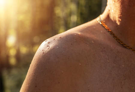 Male shoulder with water drops on tanned skin of caucasian human. Wet droplets on men body, close up.の写真素材