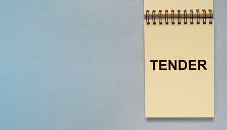 Tender word on notepad paper on blue gray background with copyspace for text. Business banner with copy space.の写真素材