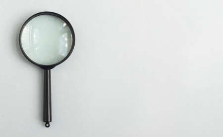 Magnifying lens over pale blue gray background with place for text. Banner with magnifier.の写真素材