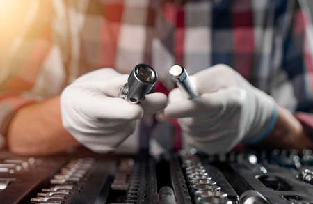Car repair tools in male hands closeup over toolkit with mechanic instruments.の写真素材