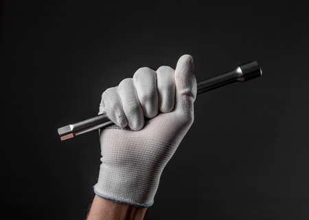 Hand in glove with metal car repair tool on black background.の写真素材