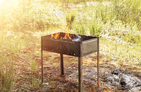 Grill with black coals and fire for bbq on grass.の写真素材