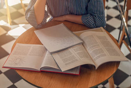 Lot of books on wood desk in modern cafe or library. Concept of research and searching answers in...